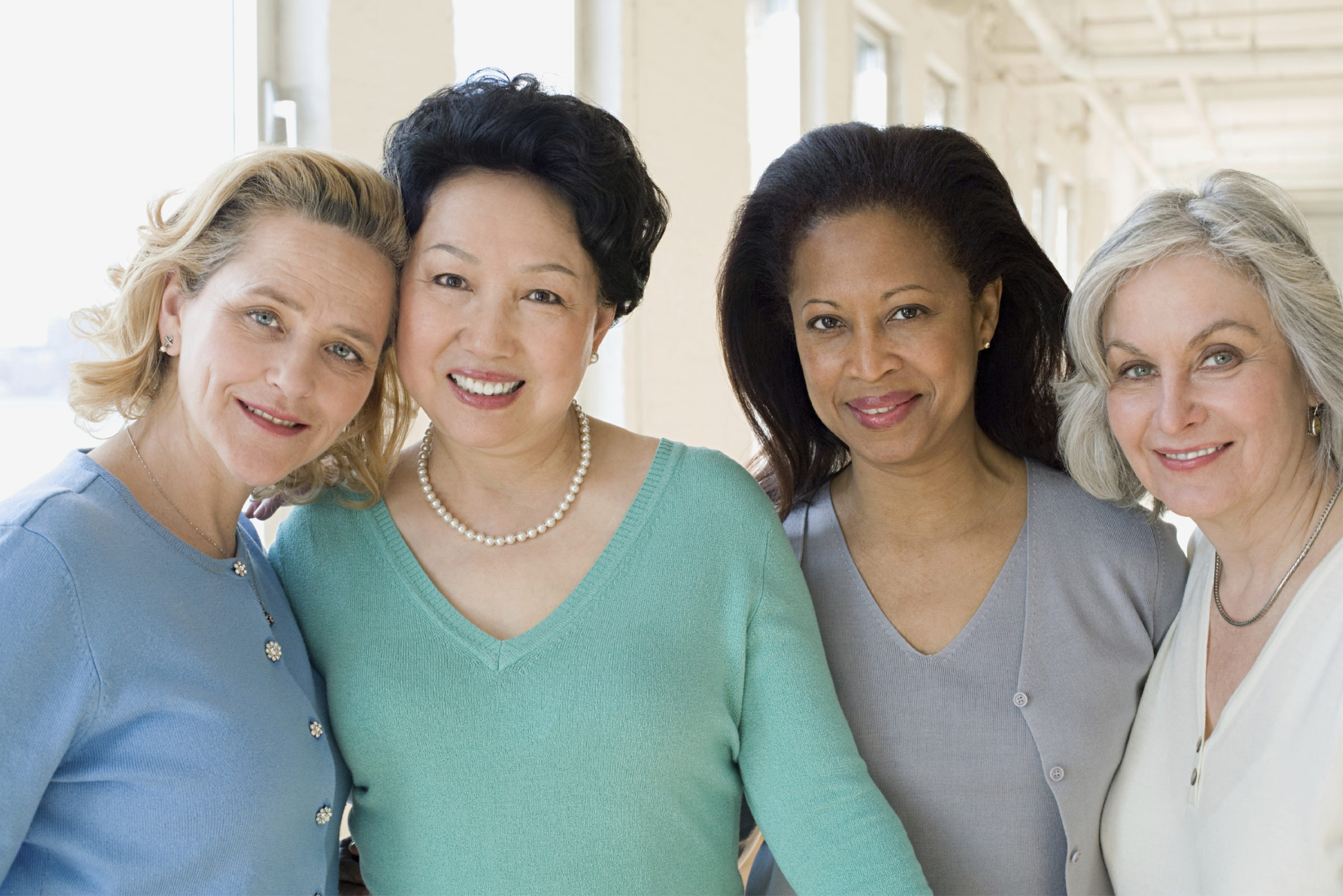four women standing together smiling. 